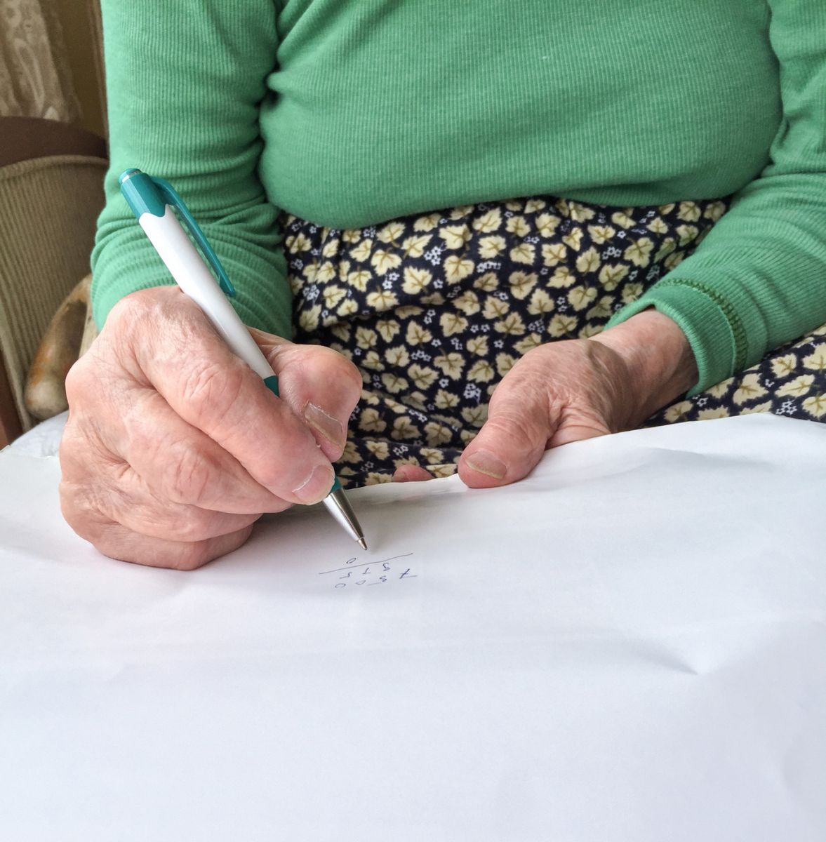 close up hands of a senior woman writing on white paper